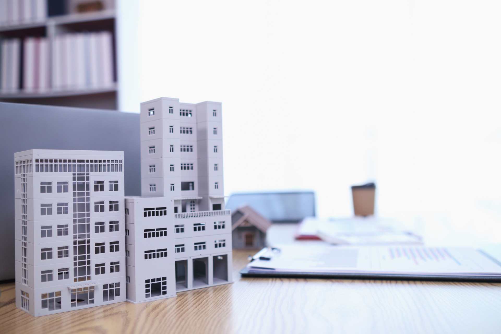 Mock up of building and documents placed on the desk of the agent in the real estate office to prepare for the customers who will come to see the property before deciding to buy the real estate.